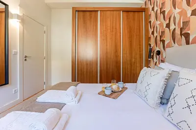 a bedroom with a white bed with a wooden headboard at Wonderful Flat Near River w/ AC by LovelyStay in Porto