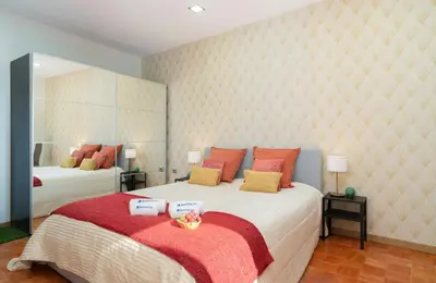 a bedroom with a large bed with red and yellow pillows at Magnificent Sunny Flat - Douro River in Vila Nova de Gaia