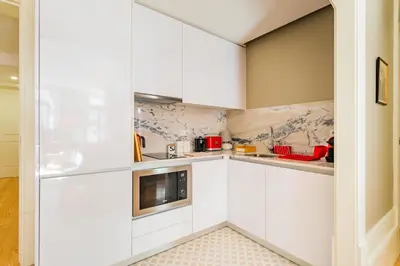 a kitchen with white cabinets and a refrigerator at Oporto Viva la Vida Central apartment in Porto