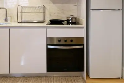 a kitchen with white cabinets and a black oven at A Window to Porto - Fabulous apartment by Douro River in Porto