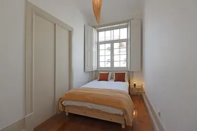a small bedroom with a bed and a window at FLH Porto Classic Apartment with Parking in Porto
