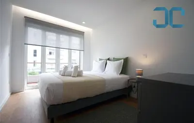 a bedroom with a white bed with a large window at Sogra Apartment by JC with Balcony in Porto