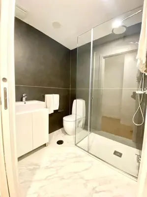a bathroom with a toilet and a glass shower at OHH-Padre Antonio Vieira Flat- HU in Porto