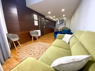 a living room with a green couch and a kitchen at OHH-Padre Antonio Vieira Flat- HU in Porto