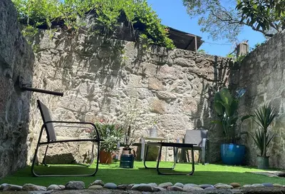 a chair and a table in front of a stone wall at Sol Garden in Porto