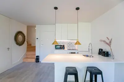 a kitchen with a white counter and two stools at Loulé Luxury Garden W/ AC in Porto