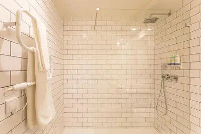 a white tiled bathroom with a shower and a sink at Loulé Luxury Garden W/ AC in Porto