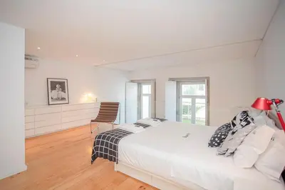 a white bedroom with a bed and a chair at Liiiving in Porto - Garden Light Mezzanine in Porto