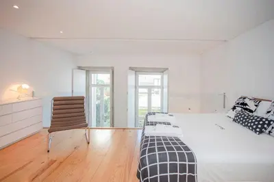 a white bedroom with a bed and a chair at Liiiving in Porto - Garden Light Mezzanine in Porto