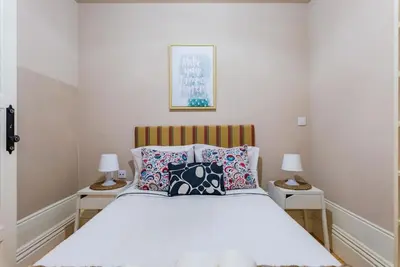 a bedroom with a white bed with pillows and two lamps at Classy Flat at Marques Square with Garden in Porto