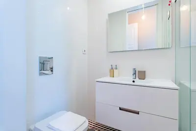 a white bathroom with a toilet and a sink at Classy Flat at Marques Square with Garden in Porto