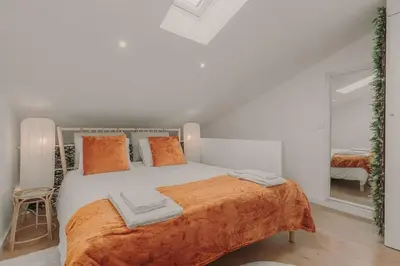 a white bedroom with a large bed with orange pillows at Nature Cosy Private House,w/AC Downtown near Metro in Porto