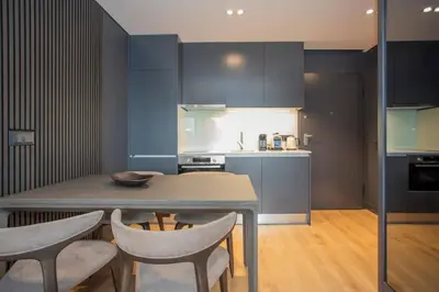 a kitchen with blue cabinets and a table and chairs at Liiiving in Porto - Dragão Pool View in Porto