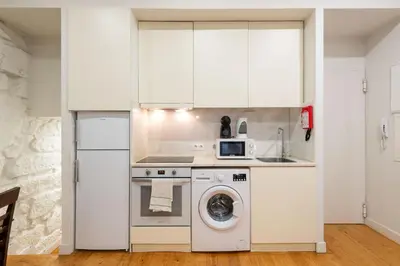 a kitchen with white cabinets and a washer and dryer at BmyGuest - Patio de Santa Catarina Apartment in Porto