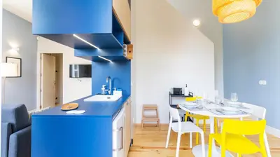 a blue kitchen with a table and yellow chairs at Barros Lima 493 by LovelyStay in Porto