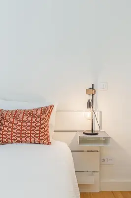 a white bed with an orange pillow and a lamp at Welcome Aliados a Noble apartment in City Heart in Porto