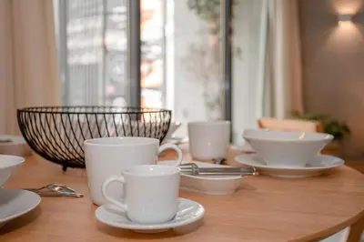 a wooden table with white cups and saucers on it at Liiiving in Porto - Bolhão Trendy Apartments in Porto