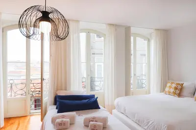 a white bedroom with two beds and a balcony at HM – Historic Downtown Batalha Studio in Porto