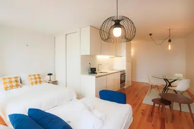 a bedroom with a bed and a table and a kitchen at HM – Historic Downtown Batalha Studio in Porto