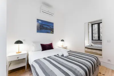 a white bedroom with a bed and a window at HiddenGem - Cherry on Top in Porto