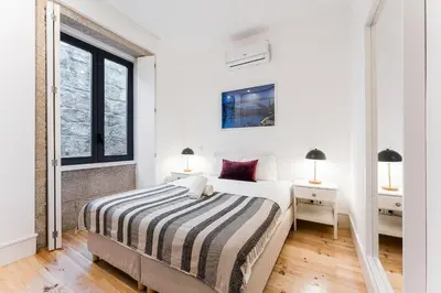 a white bedroom with a bed and a window at HiddenGem - Cherry on Top in Porto