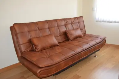 a brown leather couch with two pillows on it at Sense Porto in Porto