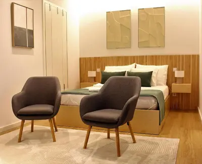 a bedroom with a bed with two chairs in it at Oporto Prime Studios in Porto