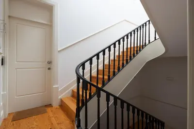 a stairway with a black rail and a white door at CASA JOY Santa Catarina apartment in Porto