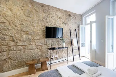 a room with a stone wall with a tv on it at Cimo de Vila 62 by LovelyStay in Porto