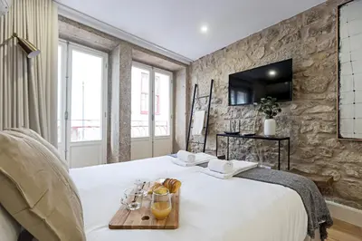 a bedroom with a bed with a tray of glasses on it at Cimo de Vila 62 by LovelyStay in Porto