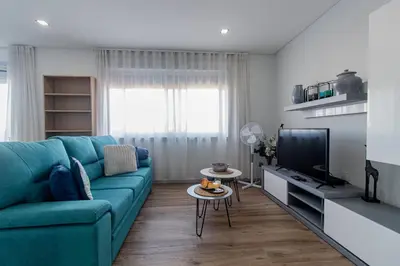 a living room with a blue couch and a tv at Downtown 1BR Apartment W/ Balcony by LovelyStay in Porto