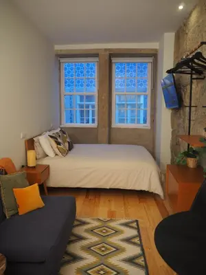 a bedroom with two beds and a couch and two windows at Casa Farrapos in Porto