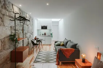 a living room with a couch and a stone wall at Casa Farrapos in Porto
