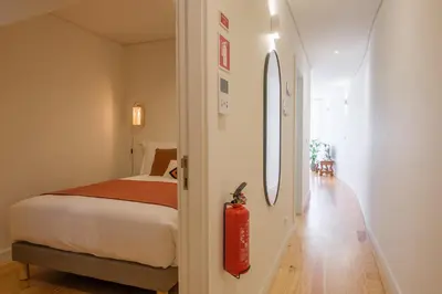 a bedroom with a bed and a red fire extinguisher at AgapeStay Porto in Porto