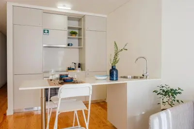 a kitchen with white cabinets and a table and a sink at AgapeStay Porto in Porto