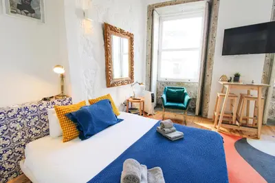 a bedroom with a large white bed and a tv at Historic Oldtown Getaway in Porto