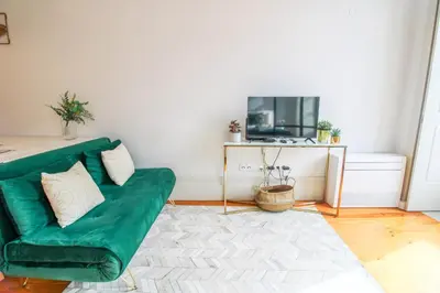 a living room with a green couch and a tv at Aliados Sunny Flat in Porto