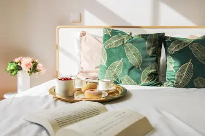 a plate of food and a book on a bed with a keyboard at Aliados Sunny Flat in Porto