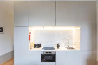 a white kitchen with a sink and a stove at Alma do Porto - With AC in Porto