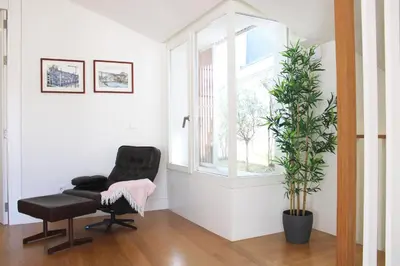 a black chair sitting in a room with a plant at Amazing Flores Duplex in Porto
