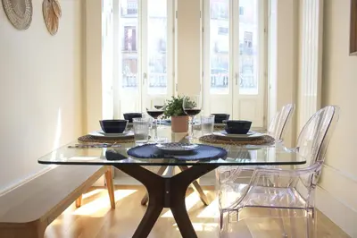 a dining room table with chairs and a glass tabletop at Amazing Flores Duplex in Porto