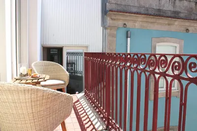 a balcony with chairs and a table and a fence at Amazing Flores Duplex in Porto