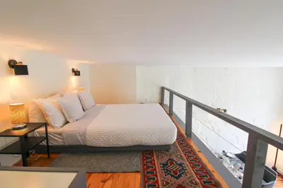 a bedroom with a bed with white sheets and pillows at Cativo Mezzanine Loft in Porto