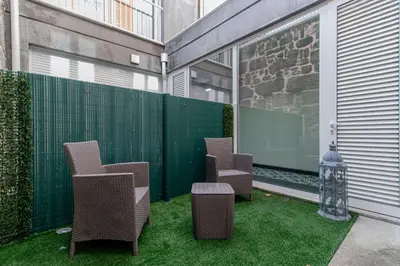 a row of chairs on a patio with grass at Cozy Studio w/ Patio by LovelyStay in Porto