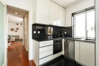 a kitchen with white cabinets and black counter tops at Feel Porto Classic Apartment in Porto