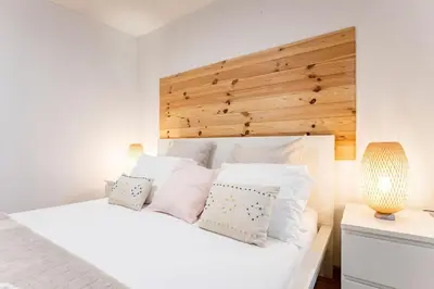 a bedroom with a white bed with a wooden headboard at Almada Hideaway w/ AC & Private Pool by LovelyStay in Porto