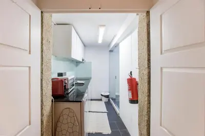 a hallway leading to a kitchen with a red fire extinguisher at Almada Hideaway w/ AC & Private Pool by LovelyStay in Porto