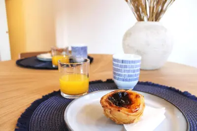 a plate with a doughnut on a table with orange juice at Living Aliados Mezzanine Flat W/ AC in Porto