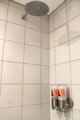 a white tiled bathroom with two cups on the wall at Living Aliados Mezzanine Flat W/ AC in Porto