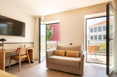 a living room with a chair and a desk and a television at The Editory Garden Porto Hotel in Porto